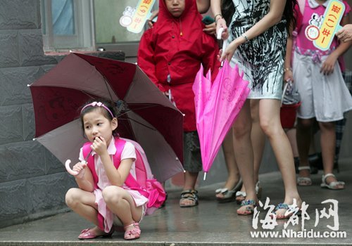 一名挤出人群的女孩,孤单地蹲在一旁等家长