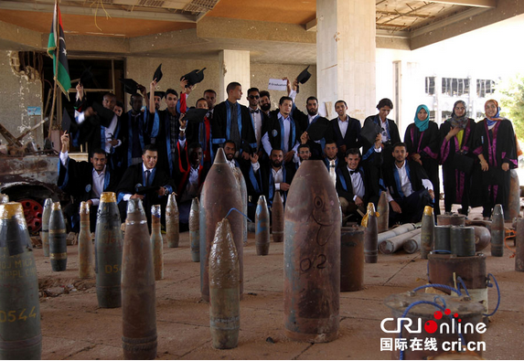 利比亚大学生在战火毁坏的教学楼前合影留念