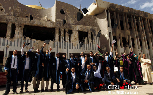 利比亚大学生在战火毁坏的教学楼前合影留念